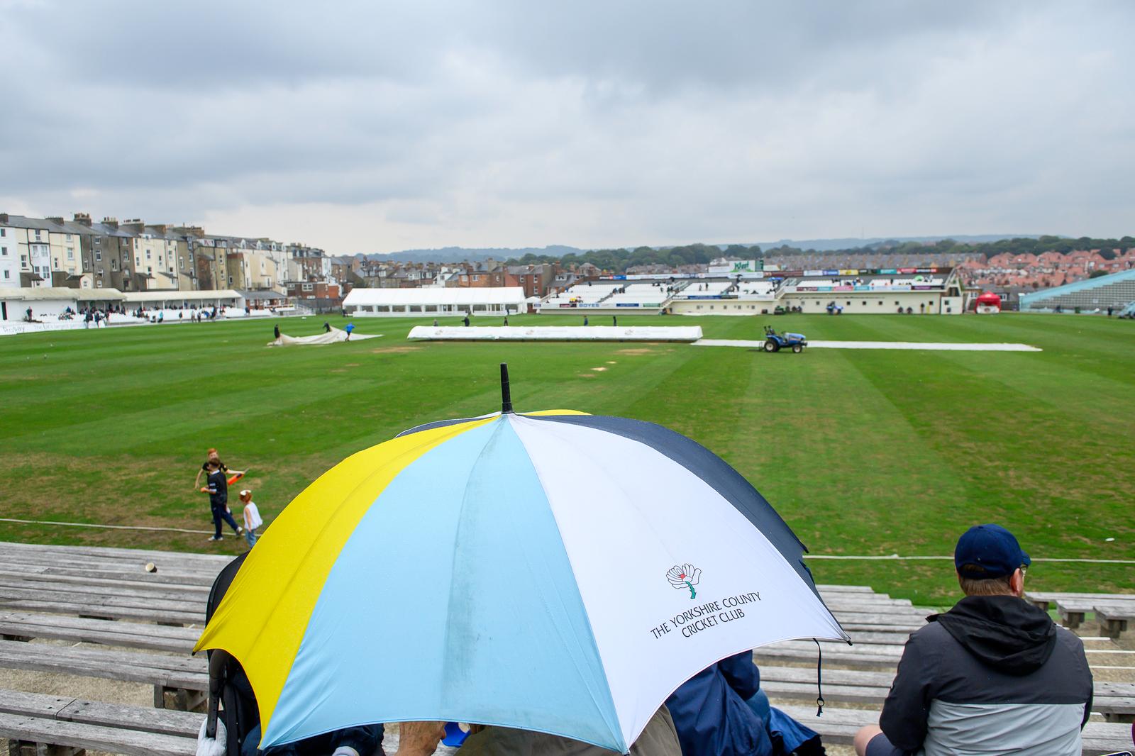 Picture by Allan McKenzie/SWpix.com - 29/08/2026 - Cricket - Rothesay County Championship - Yorkshire County Cricket Club v Leicestershire County Cricket Club - North Marine Road, Scarborough, England - Umbrellas go up as rain falls at Scarborough's North Marine Road during play between Yorkshire and Leicestershire.